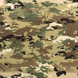 May include: A close-up of a camouflage fabric with a pattern of brown, green, and black shapes.