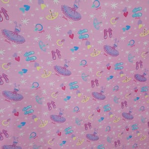 May include: Pink fabric featuring a repeating pattern of ballet dancers, ballet shoes, hearts, and stars. The word "Barbie" is printed on some of the ballet dancer images. The design includes light blue, purple, yellow, and white accents.
