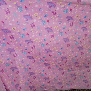 May include: Pink fabric with a repeating pattern of ballerinas, ballet shoes, hearts, rings, and stars. The ballerinas have purple tutus and are holding umbrellas. The ballet shoes are pink and white.