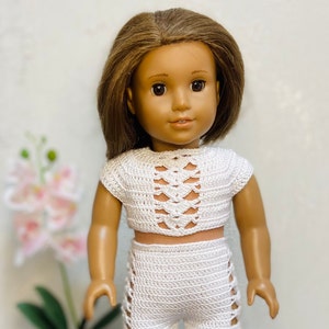 Op de afbeelding: Een wit gebreid crop top en broek set voor een pop. De top heeft een uitgesneden ontwerp en de broek heeft een zijsplit detail.