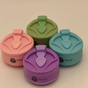 May include: Four silicone collapsible cups in different colors: green, pink, blue, and purple. Each cup has a small handle and the word "Defigo" printed on the bottom.