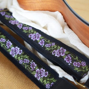 Peut inclure: Deux sangles de guitare noires avec broderie florale violette et feuilles vertes. Les sangles sont faites d'un matériau durable et comportent des extrémités en cuir et une quincaillerie en métal. Les sangles sont conçues pour être fixées à une guitare acoustique.