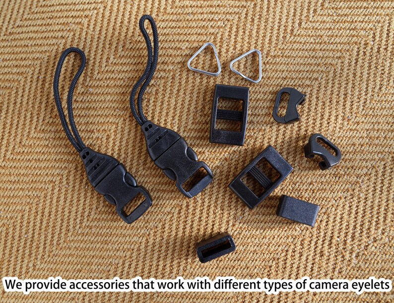 May include: A collection of black camera accessories, including buckles, straps, and metal triangle rings, are arranged on a textured tan surface. The image includes the text: "We provide accessories that work with different types of camera eyelets."
