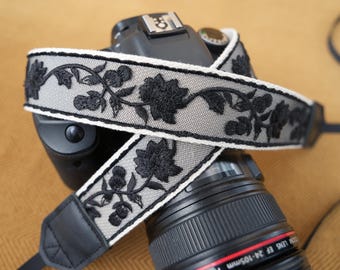 Correa de cámara negra con encaje bordado floral, hecha a mano en algodón y lino con extremos de cuero, cómoda para cámaras DSLR y sin espejo.