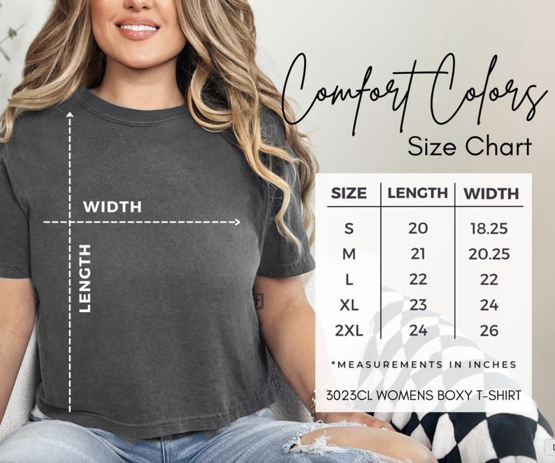 Pode incluir: Uma t-shirt boxy Comfort Colors cinza escuro com uma tabela de tamanhos. A tabela mostra as medidas em polegadas para os tamanhos S a 2XL. O texto "Comfort Colors" e "Size Chart" tamb&eacute;m s&atilde;o vis&iacute;veis.