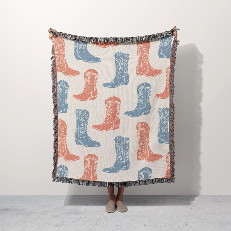 May include: A woven throw blanket with a pattern of blue and orange cowboy boots. The blanket has fringe on all sides.