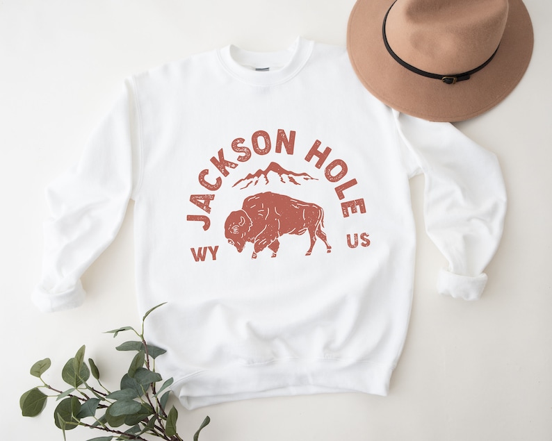 May include: White sweatshirt with a red graphic print of a buffalo, mountains, and the text "JACKSON HOLE WY US".