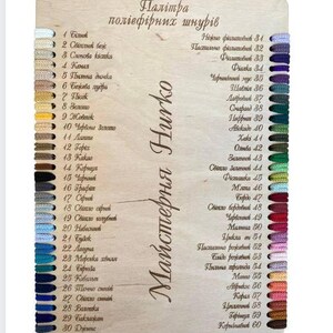 K&ouml;nnte beinhalten: Holzfarbpalette mit einer Vielzahl farbiger F&auml;den. Die Palette umfasst eine Reihe von Farben von Wei&szlig; bis Schwarz, mit Schattierungen von Blau, Gr&uuml;n und Rot. Der Text auf der Palette lautet "Hurko Workshop".