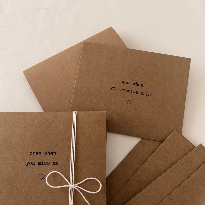 May include: Set of six brown kraft paper cards with white twine. Each card has a different message printed on it, including "open when you miss me" and "open when you receive this".