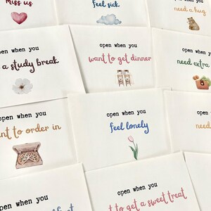 May include: A set of ten cards with different illustrations and phrases. Each card has a different message, such as "open when you need a study break" or "open when you feel lonely".