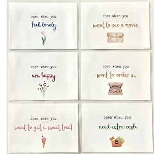 May include: Six white cards with colorful text and illustrations. The cards read: "open when you feel lonely", "open when you want to see a movie", "open when you are happy", "open when you want to get a sweet treat", "open when you want to order in", and "open when you need extra cash".