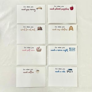 May include: Eight white cards with blue and pink text. Each card has a different illustration and text. The text on the cards reads: "for when you need gas money", "for when you need school supplies", "for when you want to eat out", "for when you need new clothes", "for when you need self care", "for when you need a movie night", "for when you need coffee", "for when you need a ride".