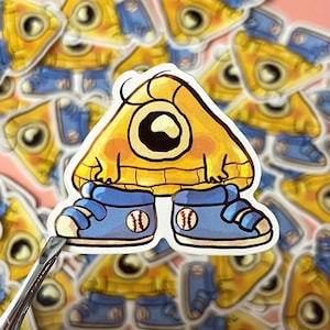 May include: A yellow triangle-shaped character with a single eye and a yellow sweater, wearing blue sneakers with white baseballs on them. The character is a sticker.