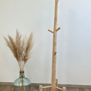 May include: A natural wood coat rack with a tall, branch-like design and a sturdy base. The rack has multiple branches for hanging coats, hats, or scarves.