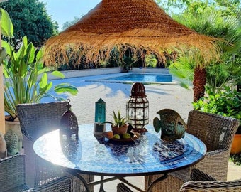 May include: A wicker patio set with a round glass mosaic table and four chairs. The table has a woven straw lampshade hanging above it. There are decorative lanterns and a blue fish figurine on the table.
