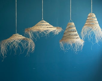 May include: Four woven straw pendant lights hanging from the ceiling against a teal blue wall. The lights are all different shapes and sizes.
