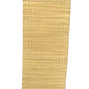 Puede incluir: Una cinta tejida de color beige natural. La cinta tiene un brillo sutil y un tejido texturizado.