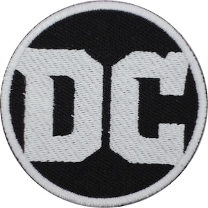 Könnte beinhalten: Ein runder Aufnäher mit dem weißen "DC"-Logo auf schwarzem Hintergrund. Das Logo ist fett und stilisiert, mit einem weißen Rand. Der Aufnäher ist wahrscheinlich ein Emblem für eine Comic- oder Unterhaltungsmarke.