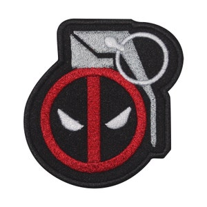 May include: Black and red embroidered patch of a grenade with a Deadpool logo on the front. The grenade has a silver pull ring and a black fuse.