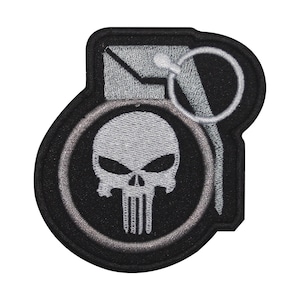 May include: A black and white embroidered patch featuring a skull with a grenade pin. The skull is surrounded by a black circle with a white outline. The grenade pin is silver.