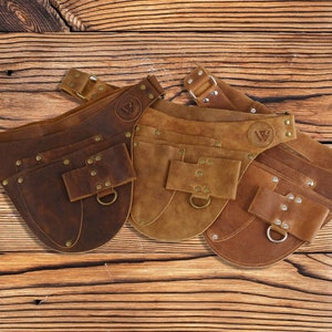 May include: Three brown leather tool belts with multiple pockets and a metal buckle. Each belt has a logo with the letters "VG" in a circle.