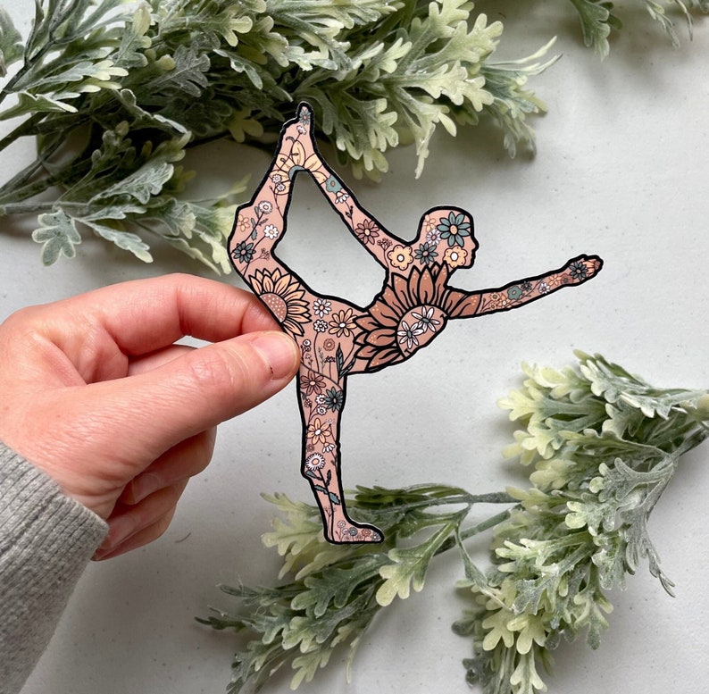 May include: A sticker of a person in a yoga pose, outlined in black, with a floral pattern inside the silhouette. The flowers are in shades of pink, yellow, and blue.