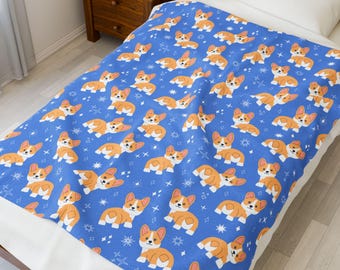 Könnte beinhalten: Eine blaue Decke mit einem sich wiederholenden Muster von Cartoon-Corgi-Hunden. Die Corgis sind orange und weiß, mit schwarzen Augen und Nasen. Weiße Sterne und Diamanten sind über die Decke verstreut.