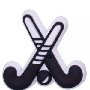 May include: A white and black hockey-themed charm featuring two crossed hockey sticks and a hockey ball. The sticks are black with white accents, and the ball is black with a white highlight. This charm is perfect for hockey enthusiasts.