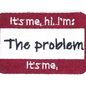 May include: Embroidered patch with a rectangular shape and rounded corners. The patch has a white centre with the words "The problem" in black script. The top and bottom borders are red with the phrases "It's me, hi, I'm" and "It's me," in white.