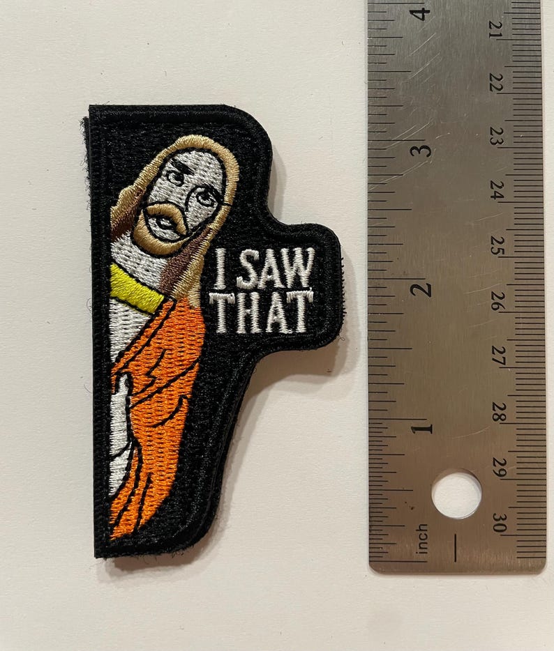 May include: A black and orange embroidered patch featuring a cartoon image of Jesus and the text "I SAW THAT".
