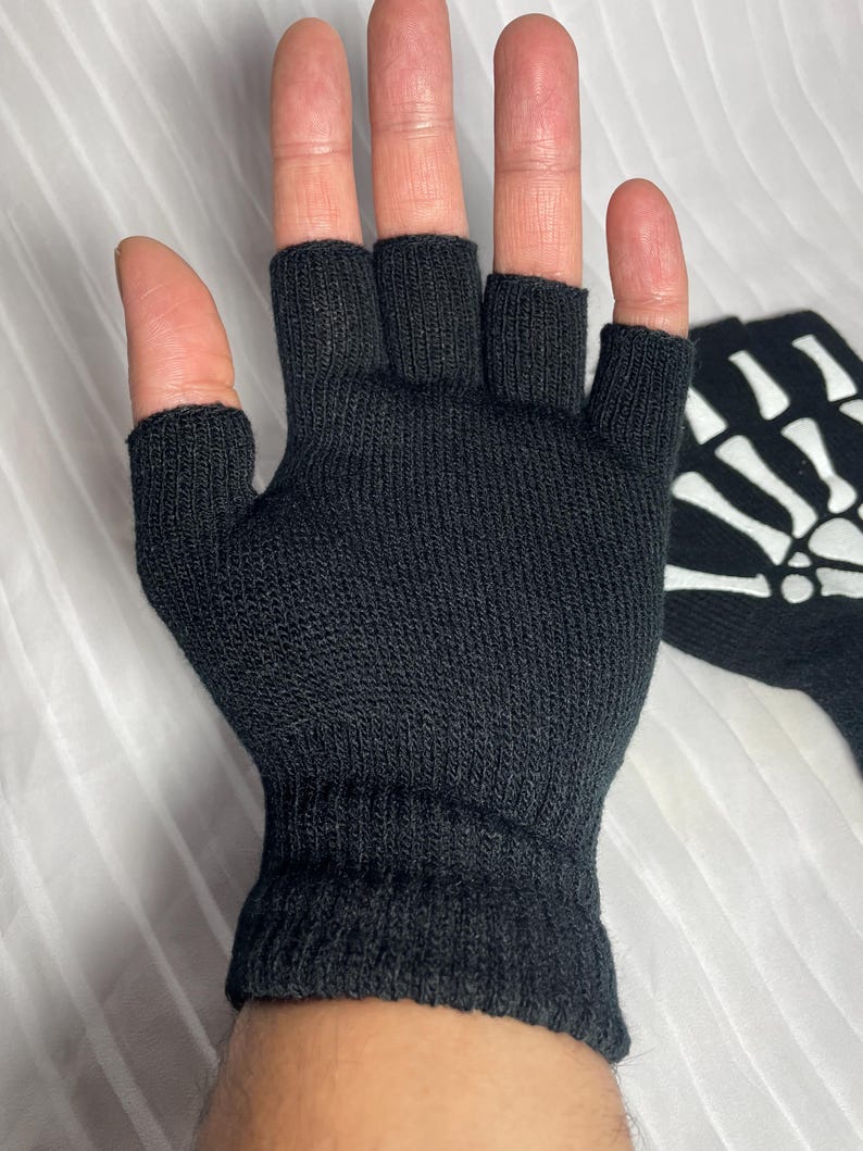 May include: Black fingerless gloves with a white skeleton design on the back of the hand.
