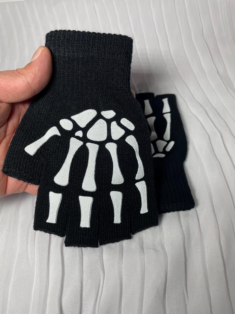 May include: A pair of black fingerless gloves with a white skeleton design.