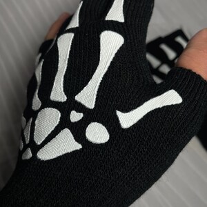 May include: Black fingerless gloves with a white skeleton design.