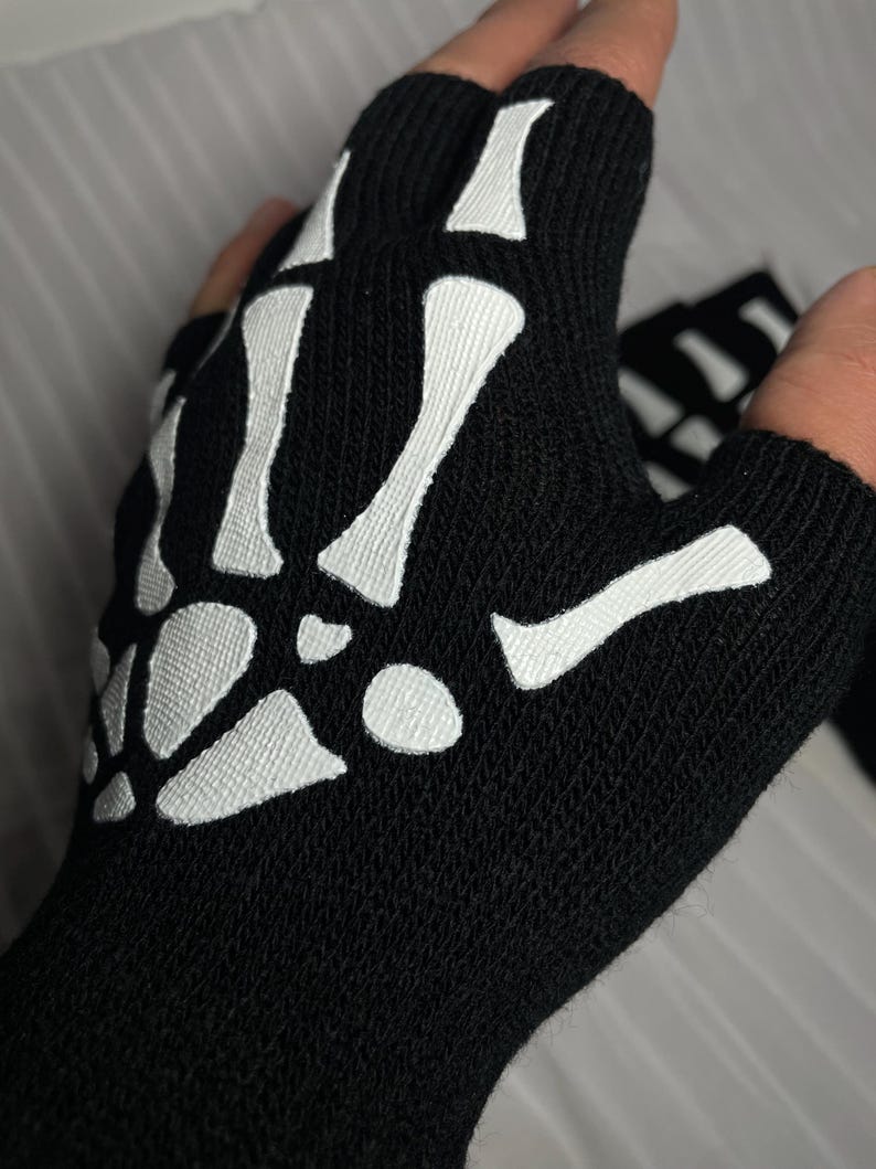 May include: Black fingerless gloves with a white skeleton design.