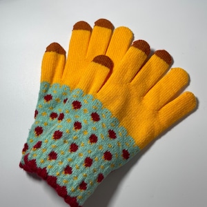 Könnte beinhalten: Ein Paar gelbe Strickhandschuhe mit braunen Fingerspitzen. Der Handgelenkbereich hat ein hellblaues Muster mit roten und gelben Punkten. Die Handschuhe sind für die Verwendung mit Touchscreen-Geräten konzipiert.