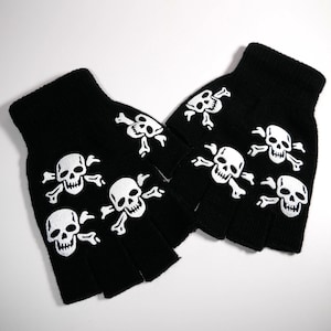Può includere: Guanti senza dita neri con disegni di teschi e ossa incrociate bianche. I guanti sono in maglia e presentano un motivo a teschio e ossa incrociate sul dorso di ogni mano. Un accessorio in stile gotico o punk.