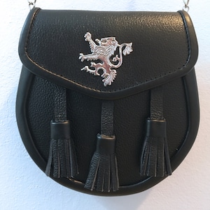 May include: Black leather bag with a silver lion emblem and three black tassels. The bag has a chain strap.