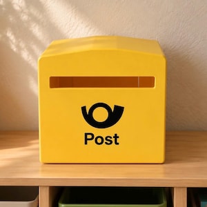 Könnte beinhalten: Ein leuchtend gelber Briefkasten mit einem horizontalen Einwurfschlitz an der Oberseite und einem schwarzen Posthorn-Logo, unter dem das Wort Post steht. Der Briefkasten hat eine glatte, matte Oberfläche und eine leicht gewölbte Oberseite.