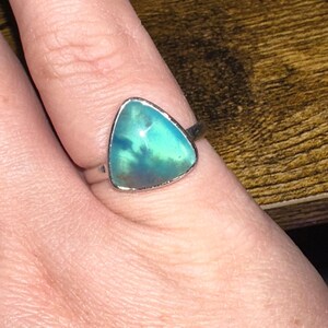 May include: A silver ring with a triangular green and blue opal gemstone.