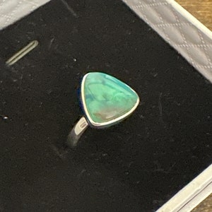 May include: A silver ring with a triangular green opal gemstone.