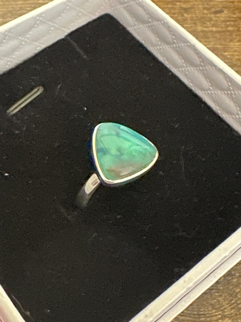 May include: A silver ring with a triangular green opal gemstone.