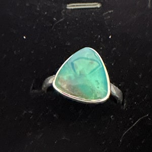 May include: A silver ring with a triangular green gemstone.