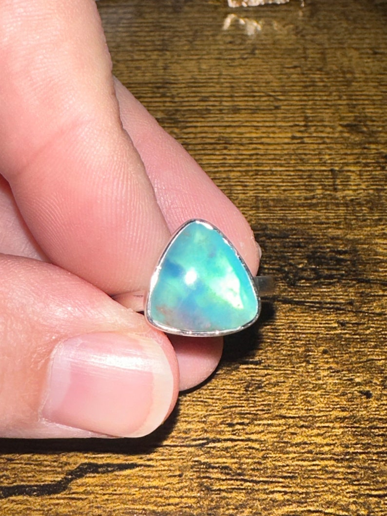 May include: A silver ring with a triangular blue opal gemstone.