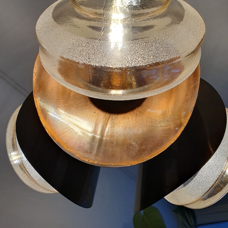 May include: A multi-tiered pendant light fixture with a copper and gold finish. The top tier is a frosted glass dome, the middle tier is a copper bowl, and the bottom tier is a black metal ring.