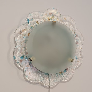May include: A white ceiling light fixture with a frosted glass shade and a decorative, scalloped, iridescent glass frame.