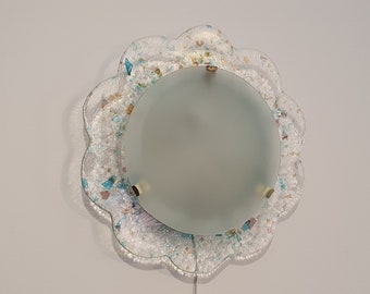 May include: A white ceiling light fixture with a frosted glass shade and a decorative, scalloped, iridescent glass frame.