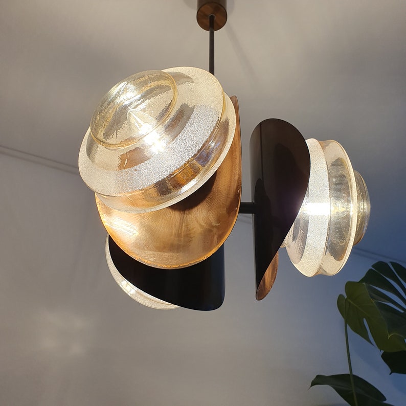 May include: A modern, multi-layered pendant light fixture with three frosted glass shades and a black metal frame. The shades are layered in a unique, geometric pattern.