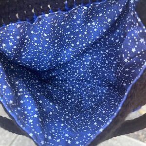May include: A blue crocheted bag with a white star patterned lining. The bag has a black crocheted handle.