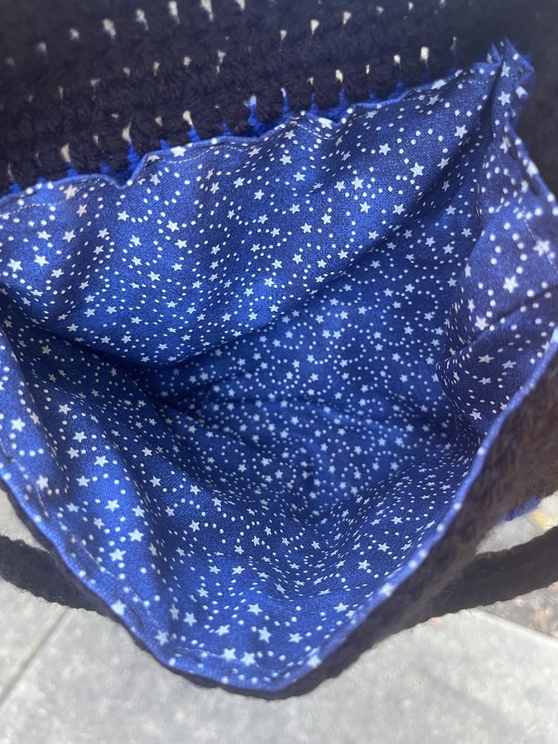 May include: A blue crocheted bag with a white star patterned lining. The bag has a black crocheted handle.