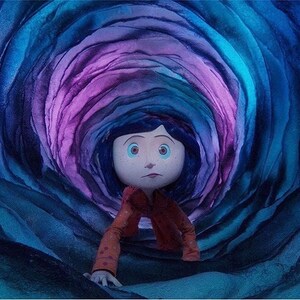 May include: A young girl with blue eyes and dark hair crawls through a swirling, multi-colored tunnel. The tunnel is made of layered, textured paper, with shades of blue, purple, and pink.